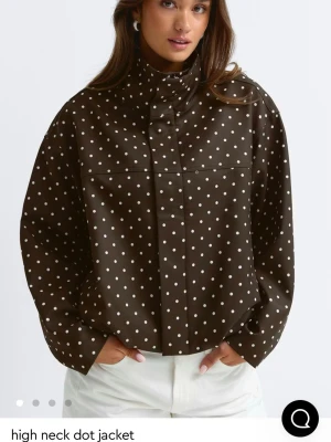 Brun prickig jacka med hög krage - Snygg brun jacka med vita prickar och hög krage. Slutsåld på hemsidan, nypris 700kr 