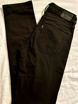 Levi's 712 Slim Jeans – Storlek 24, XS, XXS (Nyskick!) - Säljer ett par klassiska svarta Levi's 712 Slim i absolut nyskick.  De är endast använda inomhus vid ett tillfälle och har kvar sin djupsvarta färg helt utan tvättblekning. Modellen har en smal passform med medelhög midja och raka benslut, vilket ger en väldigt tidlös silhuett.  !info: Tvättlapparna på insidan är bortklippta för komfort, men lappen i midjan (W24) sitter kvar. Garanterat äkta Levi's.! Midja: ca 33cm Längd (utsida): ca 98cm Innerben: ca 72cm Benslut: ca 15cm