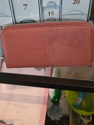 Rosa plånbok i mocka och skinn - Snygg rosa plånbok med dragkedja runtom. Framsidan har en cool mix av slätt skinn och mjuk mocka i tvådelad design. Perfekt storlek för kort och cash, och enkel att matcha med olika stilar.