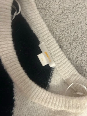 Stickad tröja från ginatricot svart/vit - Säljer en stickad tröja från ginatricot i svart och vitt med breda diagonala blockränder. Tröjan har rund halsringning och långa ärmar. Materialet är mjukt och mysigt, perfekt för kyligare dagar.