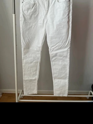 Vita skinny jeans med hög midja - Säljer ett par vita skinny jeans med hög midja och klassisk femficksdesign. Jeansen har smal passform och är tillverkade i ett stretchigt denimtyg som sitter snyggt. Perfekta att matcha med crop tops eller hoodies för en clean look.