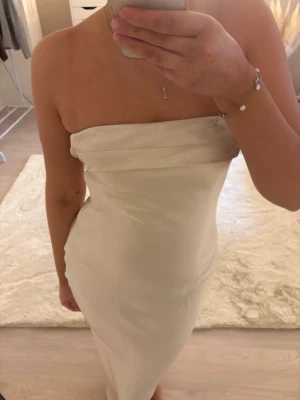 Vit axelbandslös långklänning - Elegant vit axelbandslös långklänning som passar perfekt till att ha på en bal. Från Billy J i storlek XS, köpt av en annan tjej som har haft på sig den en gång, inga defekter! 