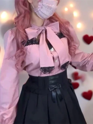 Ma*rs blus, Jirai Kei blus, Landmine blus, Rosa blus med rosett och spetsdetaljer - Supersöt rosa blus med stor rosett vid halsen och svarta spetsdetaljer längs bröstet och ärmsluten. Blusen har hjärtformade knappar framtill och puffiga långärmar för en gullig och elegant look. Perfekt för dig som gillar kawaii eller lolita-stil. *I haven’t had the opportunity to use it so I’m selling it.