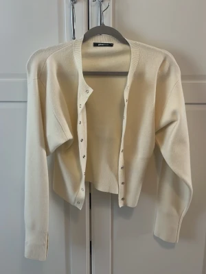 Knapp kofta från gina tricot i beiget  - En kofta med tryckknappar från gina tricot i beige som är oanvänd i storlek xs. Super fin med knappar i mitten och på armarna super fin till våren.