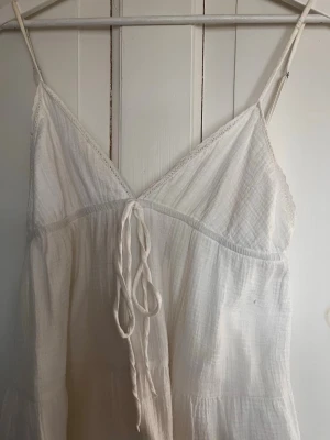 Vit sommarklänning med knytning från Zara - Luftig vit klänning med smala axelband, knytning och v-ringning. Använd ett fåtal gånger men med några små defekter, men som borde försvinna efter några tvättar. Skriv för fler bilder eller frågor