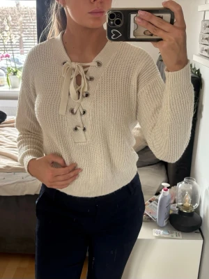Cropped stickad tröja med snörning XS- beige H&M - Fin stickad cropped tröja i en beige/cream färg med snörning framtill som ger en feminin och snygg detalj 🤍  Mjuk och bekväm, perfekt för en avslappnad men ändå stilren outfit. Den kortare modellen gör den lätt att matcha med både jeans och kjol.  Från H&M, storlek XS. I fint skick.  Jag är 170 cm och brukar ha storlek S/M – denna sitter lite mer fitted på mig ✨  En enkel men väldigt användbar topp som passar till det mesta.