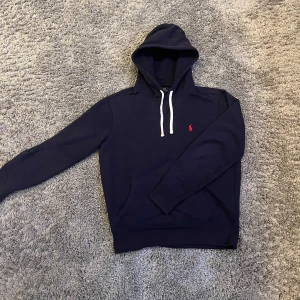 Mörkblå hoodie från Ralph Lauren - Säljer en snygg mörkblå hoodie från Ralph Lauren med en liten röd logga på bröstet. I perfekt skick