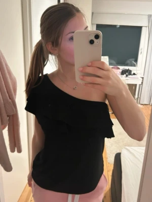 Black off shoulder top  - Stylish black off-shoulder top from H&M in size M. The top features a flattering fit and sits beautifully on the body, with an elegant one-shoulder design.  The top is in good condition, gently worn, and has no flaws. Designed with feminine ruffle details that add a chic touch. Easy to style for both everyday wear and a more dressed-up look – perfect with jeans, trousers, or a skirt.  ✔ Brand: H&M ✔ Size: M ✔ Condition: Good ✔ Color: Black ✔ Price: 150 SEK  Feel free to message me!