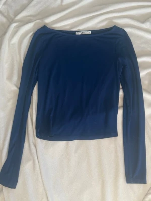 Mörkblå långärmad topp NA-KD - En enkel och stilren mörkblå långärmad topp från NA-KD. Toppen har en rund halsringning och är tillverkas i ett mjukt, stretchigt material som sitter bekvämt mot kroppen. Perfekt att matcha med jeans eller kjol.