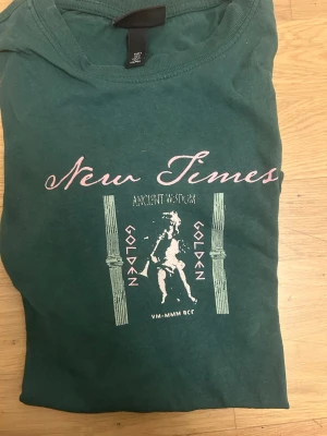 Grön t-shirt med tryck från H&M - Säljer en grön t-shirt från H&M med relaxed fit. S sitter som M