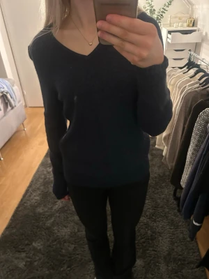 Mörkblå stickad V-ringad tröja - Mysig mörkblå stickad tröja med V-ringning och långa ärmar. Tröjan har en enkel och stilren design som passar perfekt till jeans eller kjol. Materialet känns mjukt och bekvämt mot huden. Endast använd fåtal gånger 