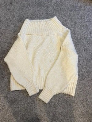 Stickad tröja  - Mysig stickad med bred ribbad krage, muddar och nederkant. Tröjan är sne skuren så den visar lite axel. Skriv vid frågor