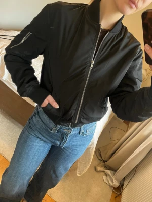 Svart bomberjacka- storlek S - Svart vårjacka med silver detaljer, två stängbara sidofickor, armficka och innerficka - Carlings  Storlek S