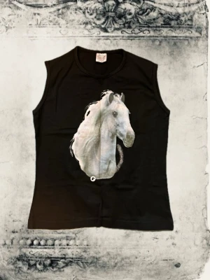 Svart ärmlös topp med hästmotiv - Cool svart ärmlös topp med ett stort vitt hästmotiv på framsidan. T-shirten har en rak passform och rund halsringning. Perfekt för dig som gillar djur och vill ha en unik look. Materialet känns mjukt och bekvämt mot huden.