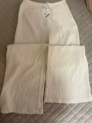 Vita strukturerade byxor från Zara - Säljer ett par vita leggings med snygg struktur. De har en avslappnad passform och är tillverkade i ett mjukt, stretchigt material som känns skönt mot huden. Perfekta för en chill och trendig look samt passar galant nu till varmare dagar💕💕💕
