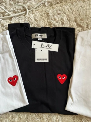 Comme des Garçons Play t-shirt - Snygg t-shirt från Comme des Garçons Play med det ikoniska hjärta med ögon broderat på bröstet. Finns i flera färger. Samt storlekar. Det är ganska små i storlekar jag skulle säga XL motsvarar L. L motsvarar M
