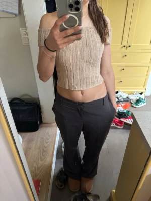 Beige ribbad offshoulder croppad topp - Trendig beige stickad topp med ribbad struktur. Offshoulder-modell och croppad passform som ger en snygg och avslappnad look. Perfekt att matcha med höga byxor eller kjol för en cool stil. Hemma stickad!!