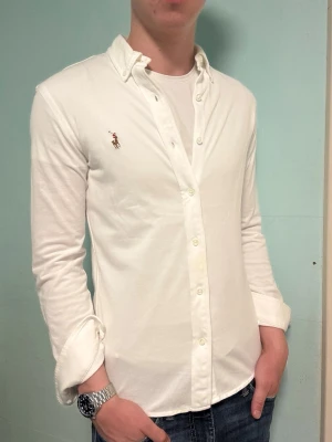 Vit Ralph Lauren skjorta – S - Säljer denna stilrena och snygga vita Ralph Lauren skjortan. Skjortan är i  mycket bra skick. Är i i skönt mjukt piké material. Har du några frågor? Tveka inte att höra av dig. Allt got Deluxe Garderoben ⭐️