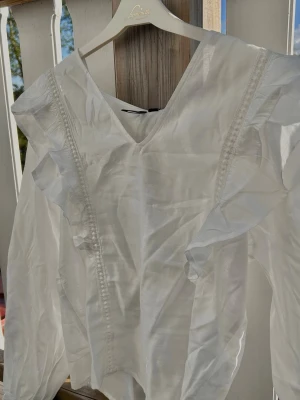 Vit blus - Superfin vit blus från Vero Moda i storlek XS. Med söta volanger och är V-ringad! Den är tunn och luftig, perfekt nu till våren/sommaren 🌸 Passar lika fint till jeans som till en kjol om man vill klä upp sig lite. Aldrig använd (pris lappen är kvar). Färgen heter Snow White och på sista bilden ser man hur genomskinlig den är🤍Orginal pris: 400kr! Obs!! Köparen står för frakten! Vid frågor eller funderingar är det bara att höra av sig🤗
