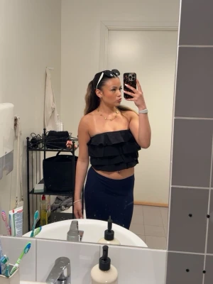 Svart volang tubtopp - Snygg svart tubtopp ifrån Zara med flera volanglager. Toppen är axelbandslös och croppad, perfekt för en trendig look. Materialet känns lätt och bekvämt mot huden.