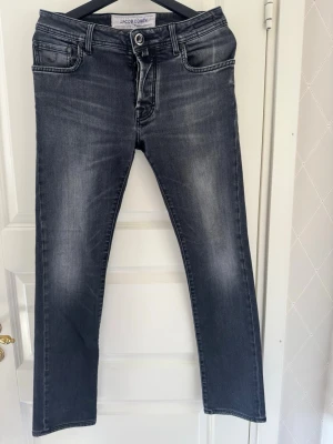 Jacob Cohen jeans - Snygga grå/svarta jeans från Jacob Cohen med raka ben och klassisk femficksdesign. Jeansen har en lätt tvättad look med subtila slitningar och kontrastsömmar. Perfekta för en avslappnad och trendig stil.