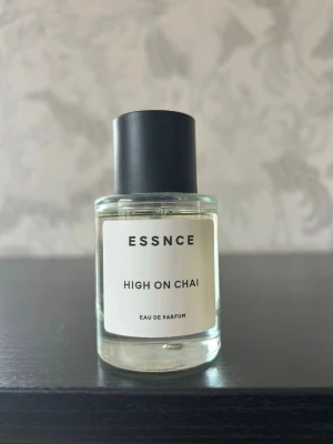 ESSNCE High On Chai Eau de Parfum - Parfymflaska från ESSNCE med doften High On Chai. Flaskan är cylindrisk i genomskinligt glas med svart rund kork och vit etikett med svart text. Modern och minimalistisk design som passar perfekt på parfymhyllan. Doftar som en chailatte. Säljer då jag har för många parfymer.