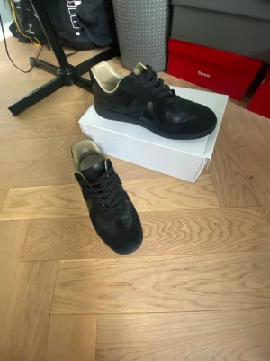 Maison margiela - Maison margiela skor äkta! Skorna har svarta skosnören och en låg siluett med beige insida. Perfekta för dig som gillar stilrena och klassiska sneakers med en modern touch.