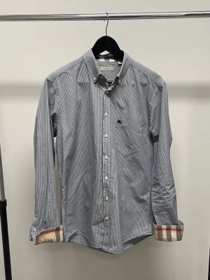 Skjorta - Blå rutig skjorta från Burberry. Fint skick och inga större tecken på användning. Det ikoniska mönstret i både ärmar och krage. Storlek M sitter som en S.