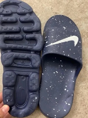 Blå Nike tofflor med vit stänkmönster - Snygga blå tofflor från Nike med vit stänkmönster och klassisk vit swoosh-logga. Gjorda i syntetmaterial med bekväm sula och öppen tå. Perfekta för chill dagar hemma eller till stranden.