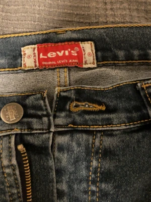 Levi's regular fit jeans blå W32 L32 - Säljer ett par klassiska blå Levi's jeans i regular fit. Jeansen är tillverkade i 100% bomull och har snygga kontrastsömmar och dragkedja. Perfekta för dig som gillar tidlös denimstil och vill ha ett par jeans som alltid funkar.
