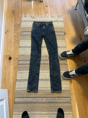 Skinny nudie jeans  - Säljer ett par mörkblå skinny jeans från Monki med klassisk femficksdesign och hög midja. Jeansen har smal passform hela vägen ner och är tillverkade i stretchigt denimtyg för extra komfort. Perfekta till en avslappnad streetstyle-look. De e mörk mörk blåa int direkt svarta.