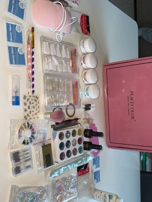 Nagellack och nagelkit från Peaccolor - Nagelkit från Peaccolor med flera nagellack i olika färger, glitter, dekorationer, penslar och verktyg. Innehåller även UV-lampa, lösnaglar, nagelgel och tillbehör för att skapa kreativa nageldesigner. Perfekt för dig som vill fixa naglarna hemma.