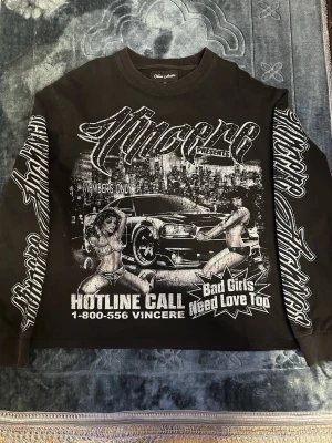 Svart sweatshirt från Vincere - Svart sweatshirt från Vincere med stora vita tryck både fram och bak. Framsidan har grafik med bil, text och motiv, medan ärmarna har Vincere-loggan i stort tryck. Materialet är mjuk bomull och tröjan har ribbade muddar vid ärmslut och nederkant. Perfekt för dig som gillar streetwear.