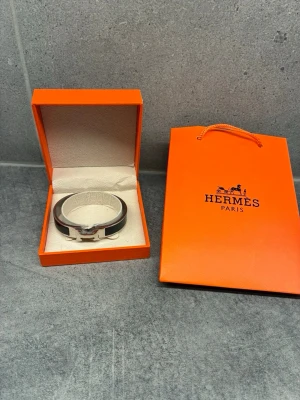 Svart armband - Snyggt svart armband i emalj och silverfärgad metall. Armbandet har den ikoniska H-detaljen framtill och kommer i originalask och påse. Perfekt accessoar för att lyfta din stil.