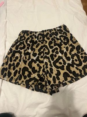 Leopardmönstrade loose shorts - Säljer ett par loose shorts med leopardmönster i beige och svart. Shortsen har resår i midjan för skön passform och är perfekta för dig som vill sticka ut lite extra. Materialet känns mjukt och lätt, perfekt för varma dagar.