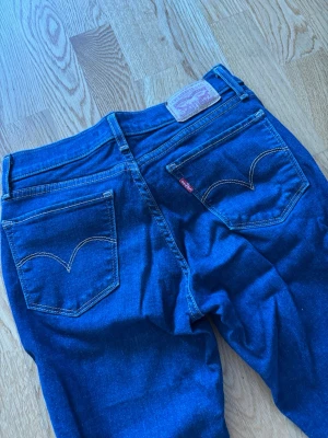 Mörkblå skinny jeans från Levi's - Säljer ett par mörkblå skinny jeans från Levi's med klassiska bakfickor och kontrastsömmar. Jeansen har normal midja, smal passform och är tillverkade i stretchigt denim för extra komfort. Perfekta för en avslappnad och trendig look.