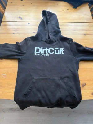 Svart Dirtcult Hoodie  - Svart Dirtcult Hoodie med vitt tryck i storlek 158/164 ganska sliten och sliten i armarna men håller ändå.