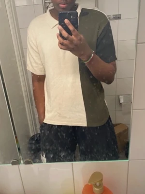 Beige och olivgrön halvzip tröja - Säljer en stilren halvzip tröja i beige och olivgrönt blockmönster. Tröjan har hög krage med dragkedja och korta ärmar. Perfekt för dig som gillar en clean och modern look. Materialet känns mjukt och bekvämt.