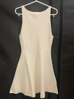 Vit klänning - Vit (crémevit) stickad klänning i nytt skick från H&M i storlek xs. Den är lätt utsvängd nertill för en feminin siluett. Perfekt för dig som gillar en stilren och enkel look.