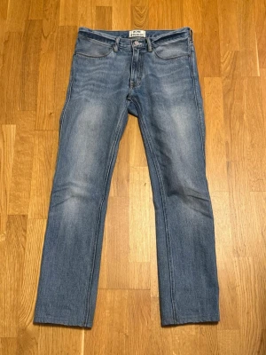 Acne Studios Jeans - Säljer ett par klassiska blå jeans från Acne Studios, modell Max LT Vintage 30x34. Jeansen har rak passform, tillverkade i 100% bomull. Snygg tvätt med lätt slitning på låren för en vintagekänsla. 