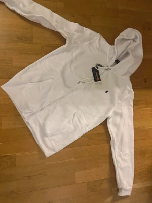 Vit hoodie från Polo Ralph Lauren - Snygg vit hoodie från Polo Ralph Lauren med dragkedja framtill och klassisk logga. Storlek M