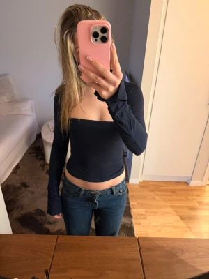 Mörkblå långärmad topp - mörkblå croppad topp med lång ärm och fyrkantig urringning. Sitter tight och har en stilren, minimalistisk look som passar perfekt till jeans eller kjol. Materialet känns mjukt och stretchigt för en bekväm passform.