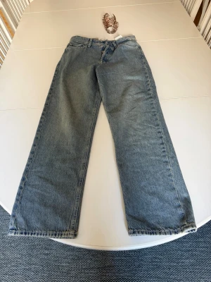 Blå raka jeans från Weekday - Säljer ett par klassiska blå jeans från Jack and Jones med rak passform och hög midja. Jeansen har fem fickor, bälteshällor och är gjorda i kraftig denim. Perfekta för en avslappnad och trendig look.