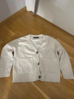 Vit kofta med stora fickor -  vit kofta med v-ringning och tre stora knappar framtill. Lämna gärna prisförslag!
