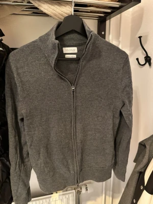 These Glory Days Grå ziptröja - Säljer en stilren grå ziptröja från Banana Republic med hög krage och hel dragkedja. Tröjan är tillverkad i mjukt material och har ribbade muddar vid ärmslut och nederkant. Perfekt för lager-på-lager och enkel att matcha. Krympt i tvätten passar XXS