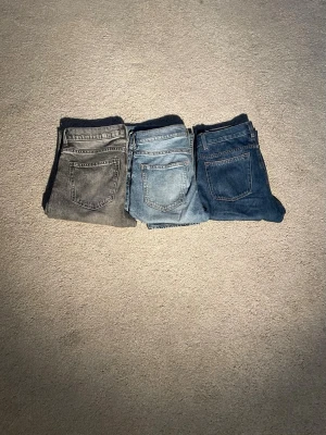 Tre par raka jeans i olika tvättar - Säljer tre par raka jeans i olika tvättar: ett par grå, ett par ljusblå och ett par mörkblå. Klassisk femficksmodell med normalhög midja och raka ben. Perfekta för dig som vill ha flera färger att variera mellan. Materialet är klassisk denim i bomull. Dem gråa och ljusblåa är från h&m och den i mörkblå är från Zara, alla tre för 219 en för 99 pris kan ev diskuteras vid snabb affär!