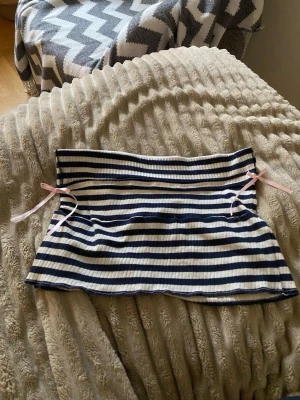 Randig mini kjol - Omsydd mini kjol med rosetter på sidorna som har ett litet fold over band