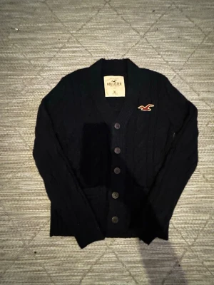 Vintage Hollister kofta - Snygg mörkblå kabelstickad kofta från hollister, tröjan är vintage som är eftertraktad. Skicket är riktigt bra då det inte finns några defekter. Storleken är XL men passar mer som en L. Startpriset börjar på 599 men kan diskuteras😊😊
