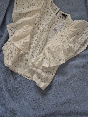 Vit spetsblus från Gina tricot  - Superfin vit spetsblus från Gina tricot med blommigt mönster och volangdetaljer på ärmarna. 