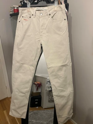 Beiga Diesel jeans - Säljer ett par beiga jeans från Diesel Modern Basic. Jeansen har rak passform, klassisk femficksdesign och detaljer i metall. Tillverkade i kraftigt bomullstyg för en clean och stilren look. Perfekta för dig som gillar enkel och tidlös stil.